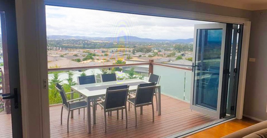 Retractable fly screen on open bifold doors in a Canberra home in summer