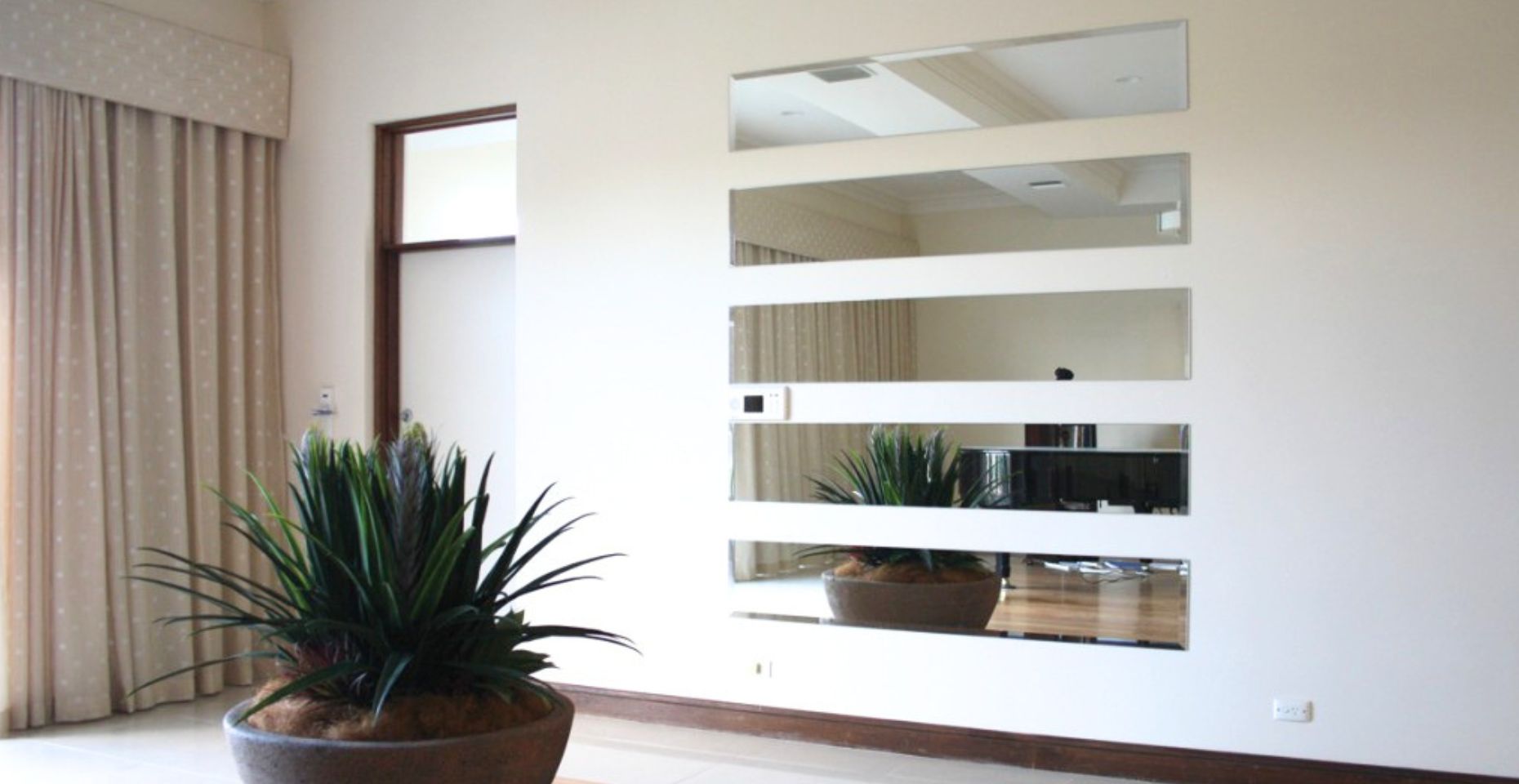 Custom-cut frameless wall mirror brightening a Canberra living room